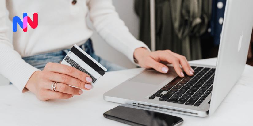 Une femme avec une carte bancaire devant son ordinateur