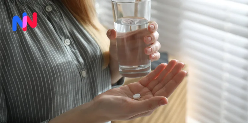 Une femme tenant un verre d'eau et un cachet